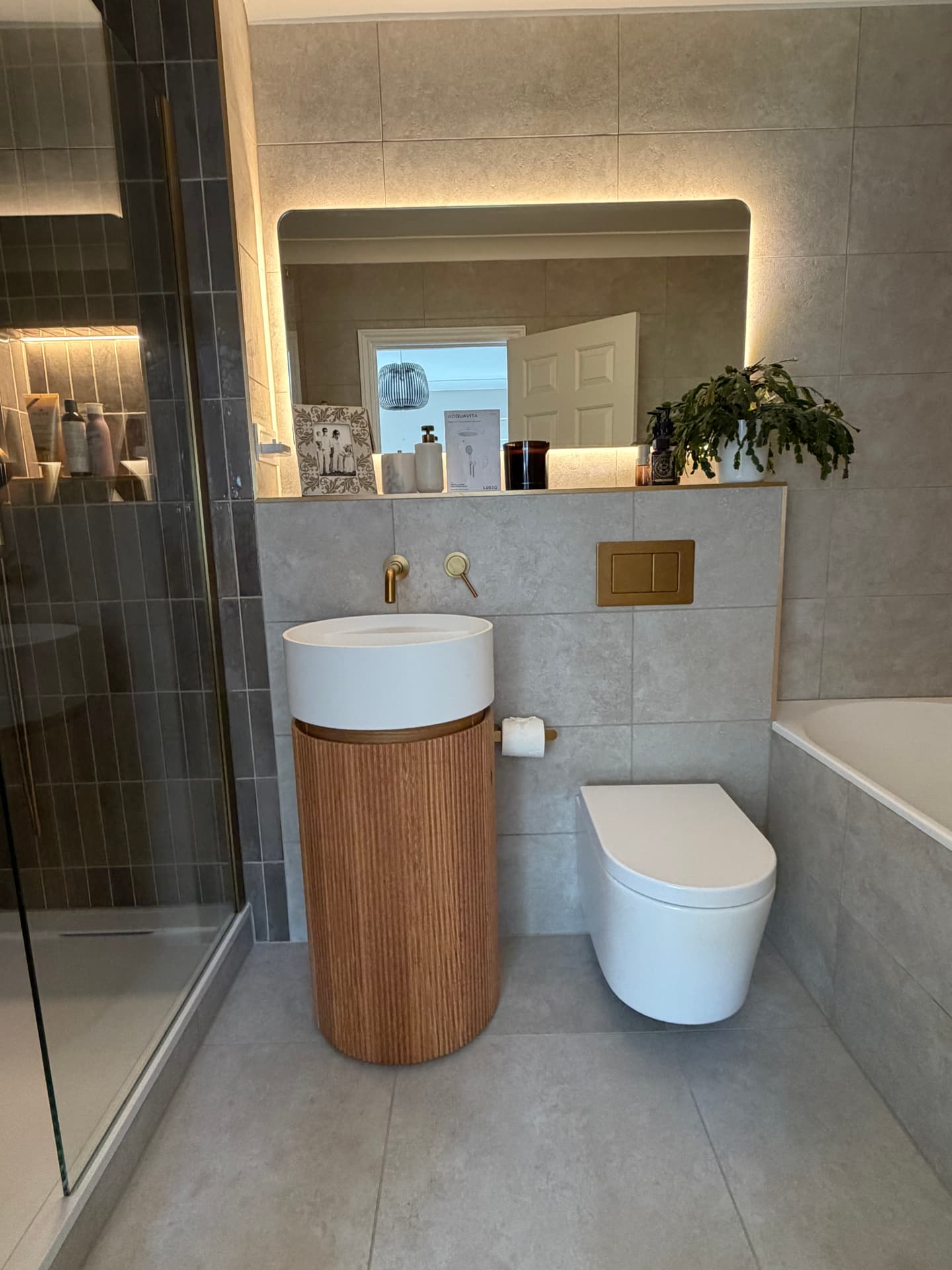 Finished bathroom with oak vanity unit, brass fittings and LED mirror
