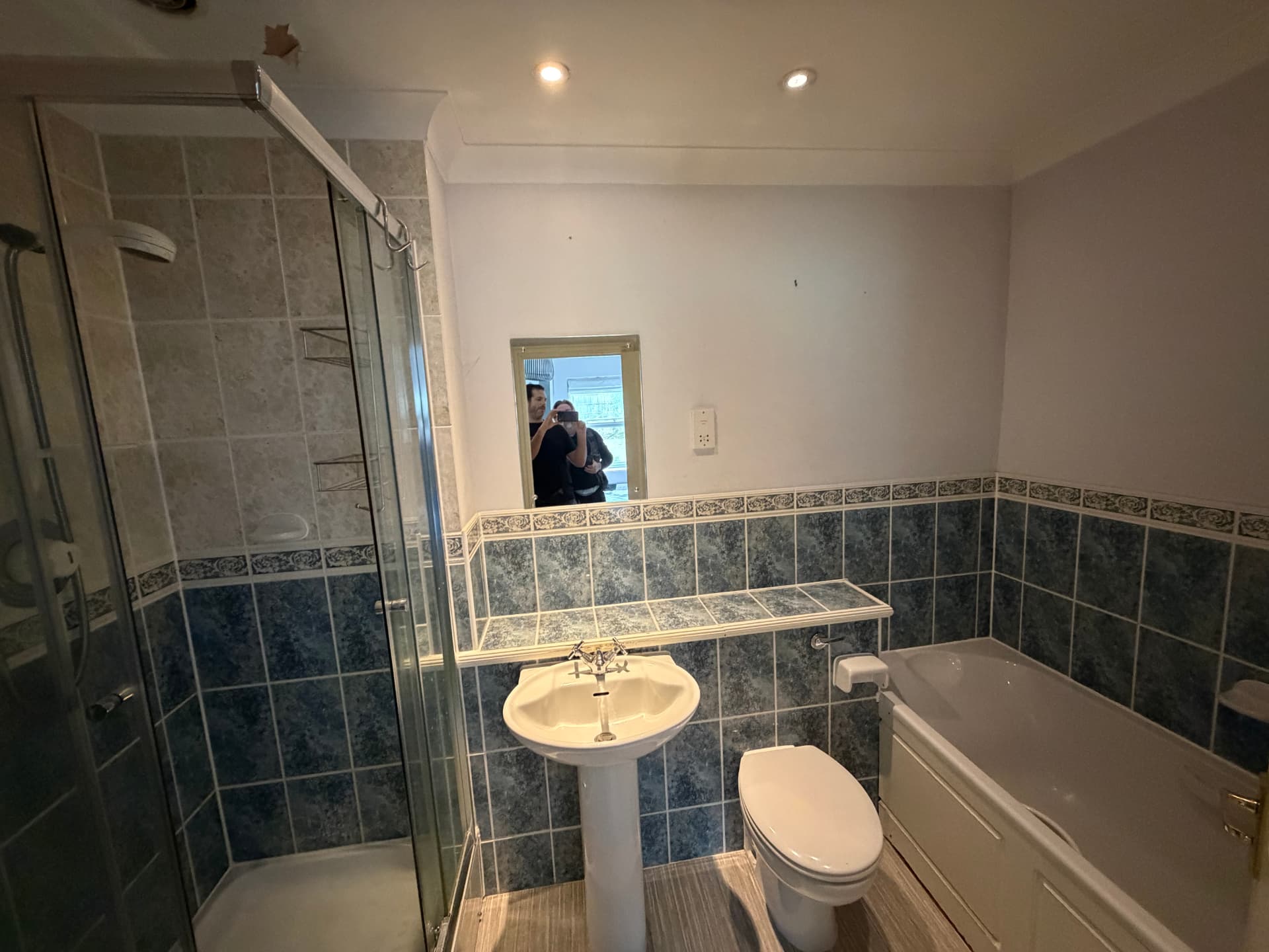 Old bathroom with blue tiles, sink, toilet and bath